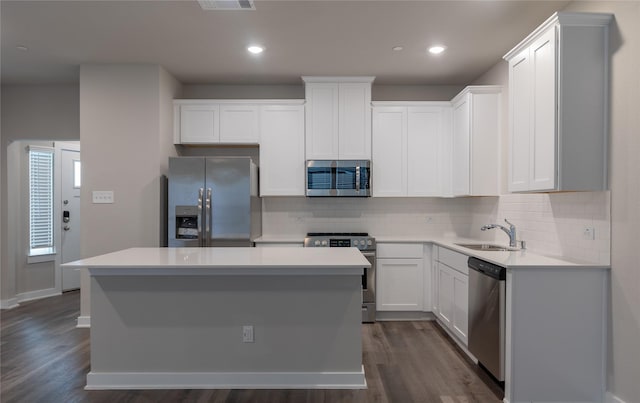 kitchen with stainless steel appliances, white cabinetry, a kitchen island, and sink