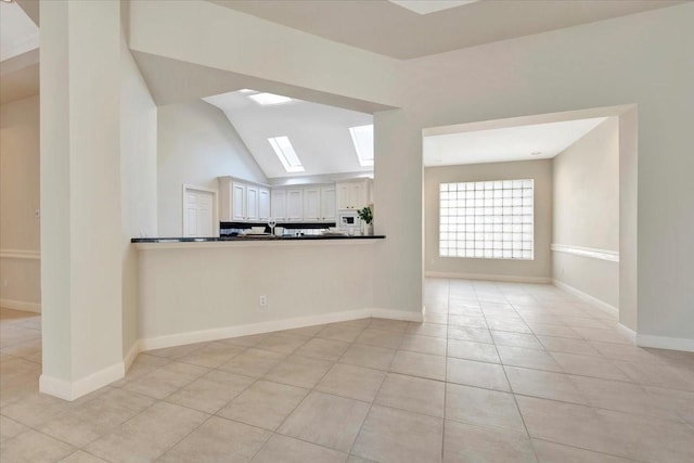 interior space with lofted ceiling with skylight and light tile patterned floors