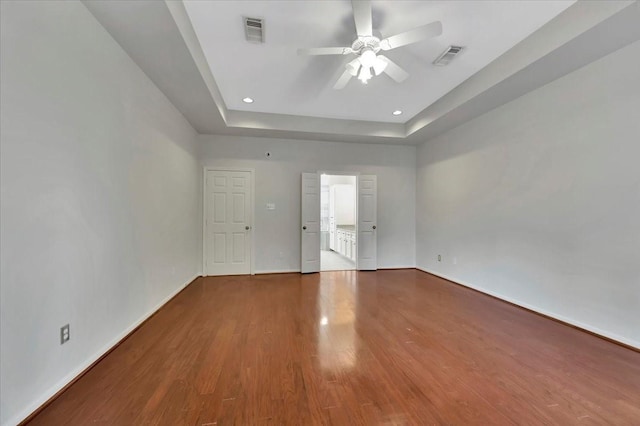 spare room featuring wood-type flooring, a tray ceiling, and ceiling fan