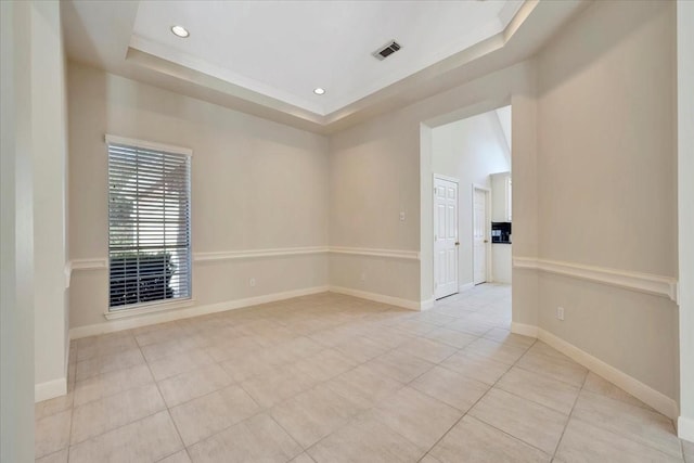 tiled empty room featuring a raised ceiling