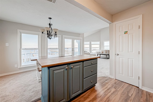 kitchen featuring wooden counters, hanging light fixtures, gray cabinets, a kitchen island, and light hardwood / wood-style floors