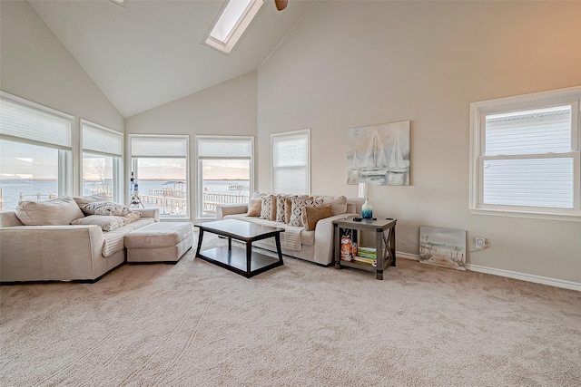 living room featuring light carpet, a skylight, baseboards, a water view, and high vaulted ceiling