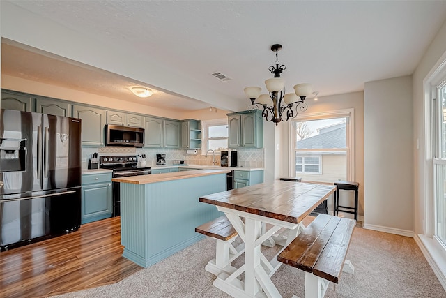 kitchen with decorative light fixtures, tasteful backsplash, visible vents, light countertops, and appliances with stainless steel finishes