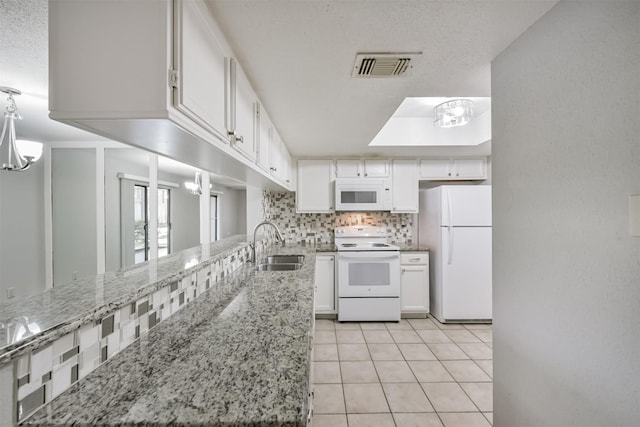 kitchen with tasteful backsplash, light stone counters, white appliances, sink, and white cabinets