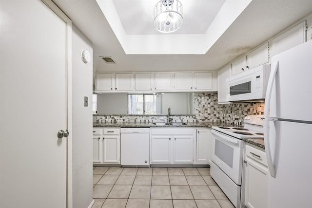 kitchen with white appliances, a tray ceiling, sink, light tile patterned floors, and white cabinetry