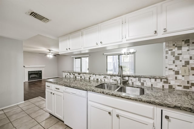 kitchen with dishwasher, a tile fireplace, sink, ceiling fan, and white cabinetry