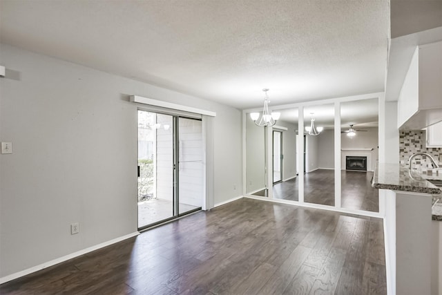 unfurnished room featuring ceiling fan with notable chandelier and dark wood-type flooring