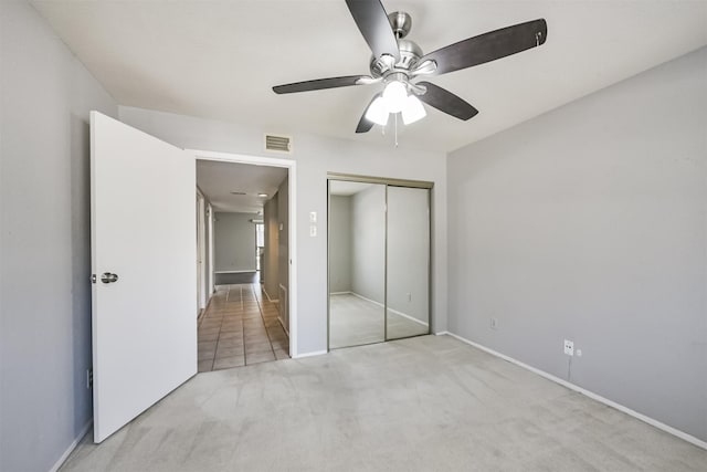 unfurnished bedroom with ceiling fan, light colored carpet, and a closet