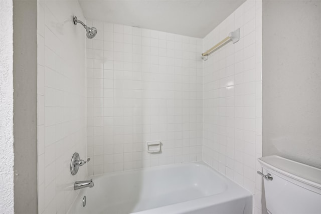 bathroom with toilet and tiled shower / bath