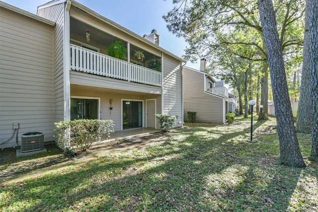 exterior space with central air condition unit, a balcony, and a lawn