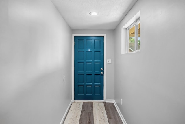 doorway featuring a textured ceiling and light hardwood / wood-style flooring