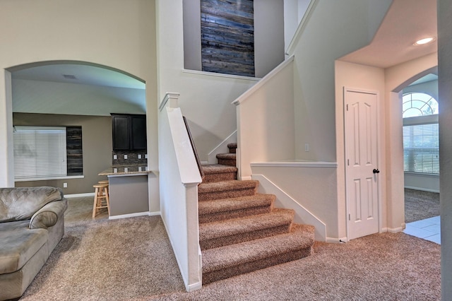 stairs with carpet and a towering ceiling