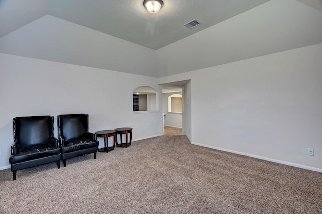 sitting room featuring carpet floors and vaulted ceiling