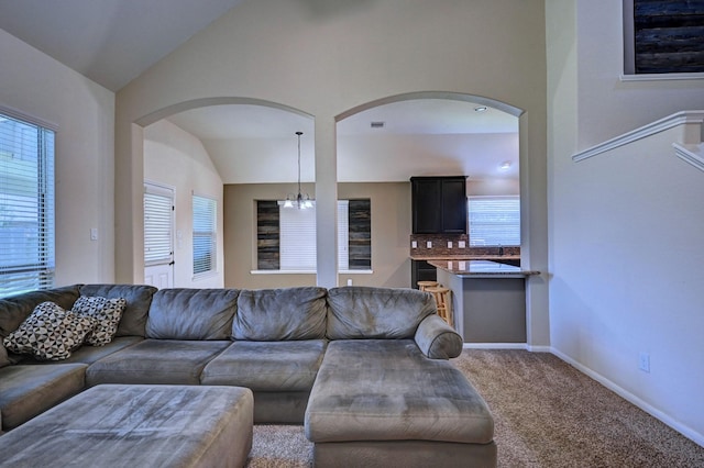 living room with carpet flooring, lofted ceiling, and a notable chandelier