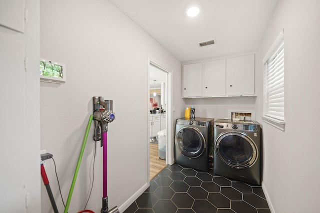 washroom featuring washing machine and clothes dryer, cabinets, and dark tile patterned flooring