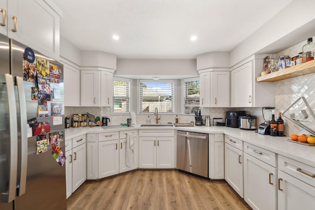 kitchen with decorative backsplash, white cabinetry, sink, and stainless steel appliances