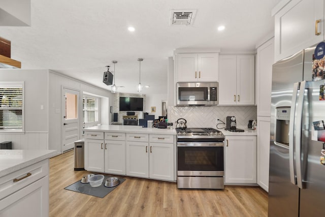 kitchen with a wealth of natural light, white cabinetry, appliances with stainless steel finishes, and light hardwood / wood-style flooring