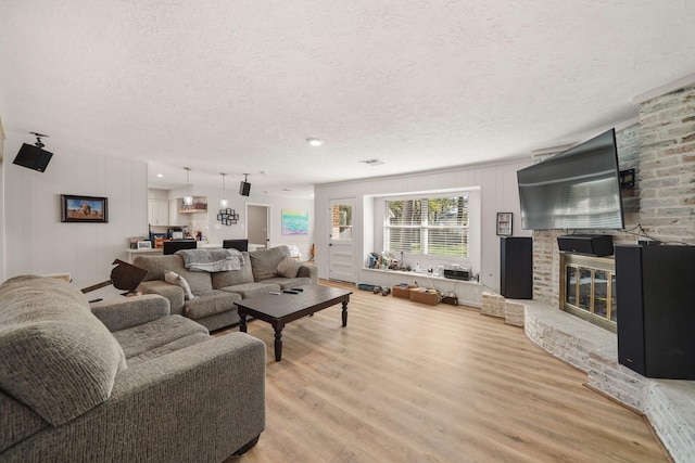 living room with a fireplace, light hardwood / wood-style floors, and a textured ceiling