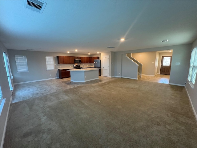 unfurnished living room featuring light carpet and sink