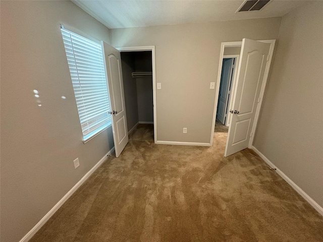 unfurnished bedroom with carpet flooring, a spacious closet, and a closet