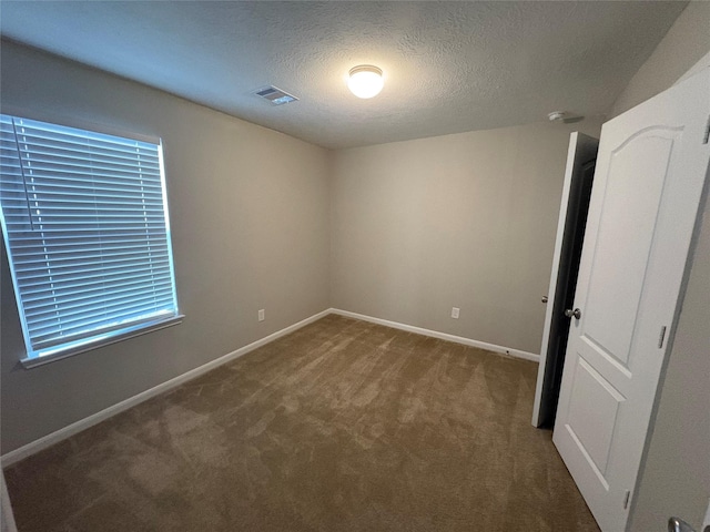 empty room with carpet and a textured ceiling