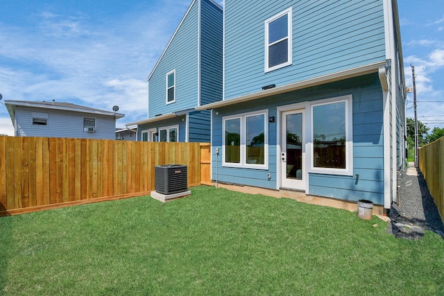 rear view of house featuring a lawn and central AC