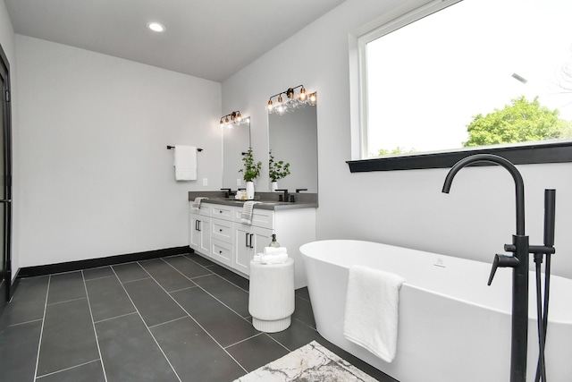 bathroom with tile patterned flooring, vanity, a wealth of natural light, and a bathing tub