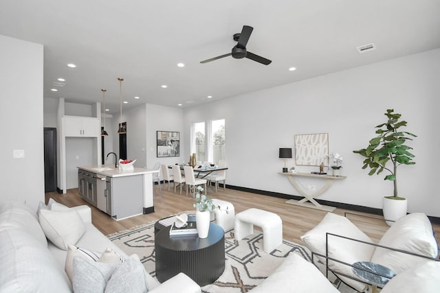 living room featuring light hardwood / wood-style flooring, ceiling fan, and sink