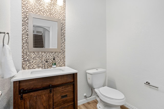 bathroom featuring decorative backsplash, hardwood / wood-style floors, vanity, and toilet