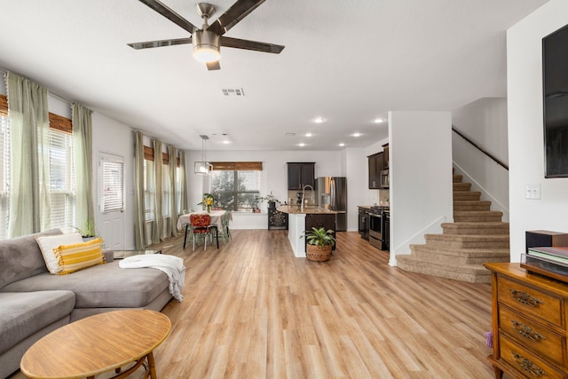 living room with ceiling fan, sink, and light hardwood / wood-style flooring