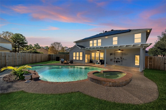 pool at dusk with a patio area, ceiling fan, and an in ground hot tub