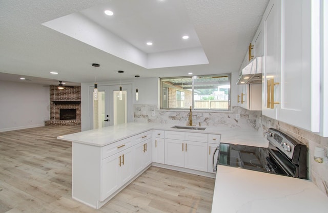 kitchen featuring sink, backsplash, kitchen peninsula, stainless steel electric stove, and white cabinets