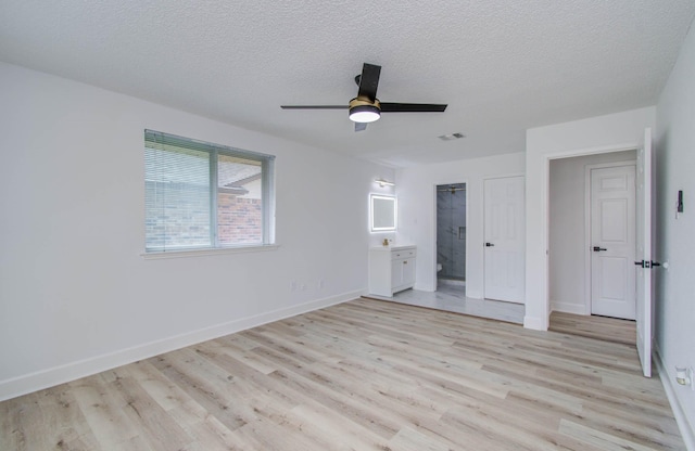 unfurnished bedroom featuring ensuite bath, ceiling fan, light hardwood / wood-style floors, a textured ceiling, and a closet