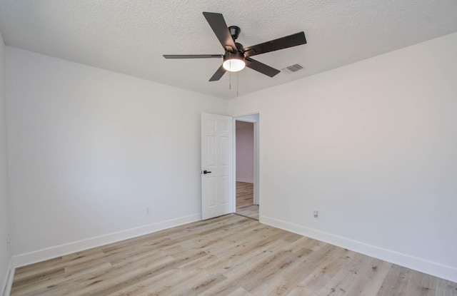 empty room featuring a textured ceiling, light wood-type flooring, and ceiling fan