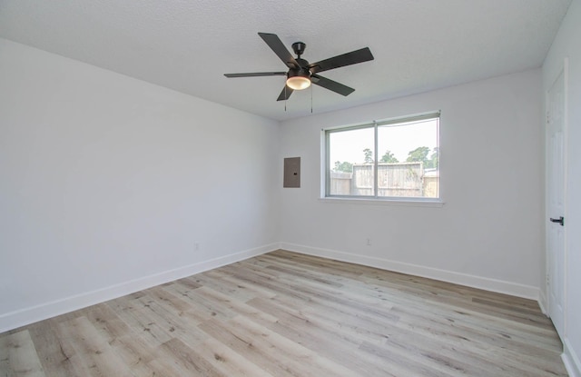 spare room featuring ceiling fan, light hardwood / wood-style floors, a textured ceiling, and electric panel