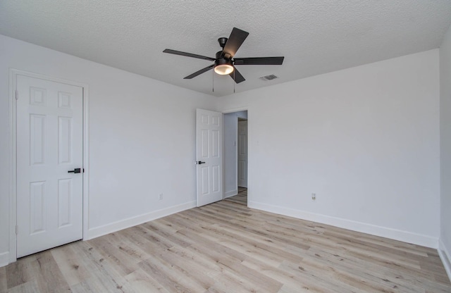 empty room featuring ceiling fan, light hardwood / wood-style floors, and a textured ceiling