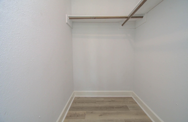 walk in closet with light hardwood / wood-style flooring