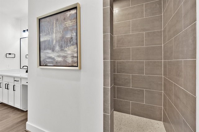 bathroom featuring tiled shower, vanity, and hardwood / wood-style flooring