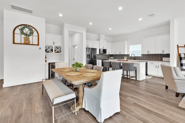 dining room featuring wine cooler, light hardwood / wood-style flooring, and sink