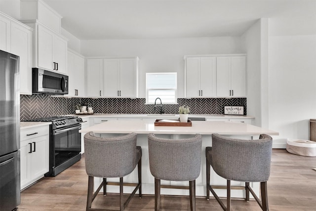 kitchen with white cabinets, a breakfast bar, a center island, and stainless steel appliances