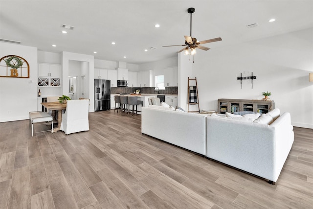 living room featuring ceiling fan, light hardwood / wood-style floors, and sink