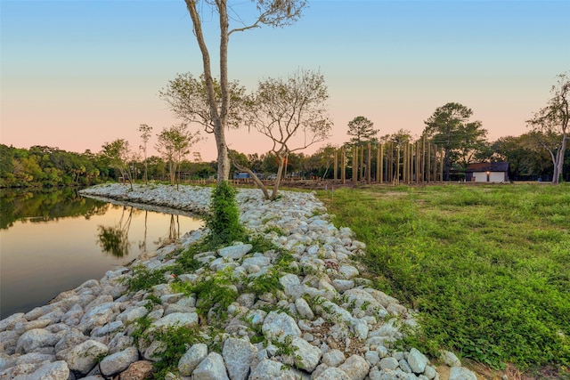 yard at dusk featuring a water view