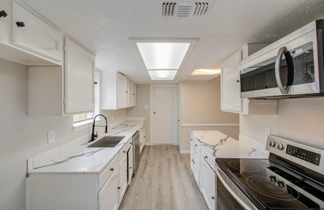 kitchen featuring light stone counters, sink, white cabinets, and stainless steel appliances