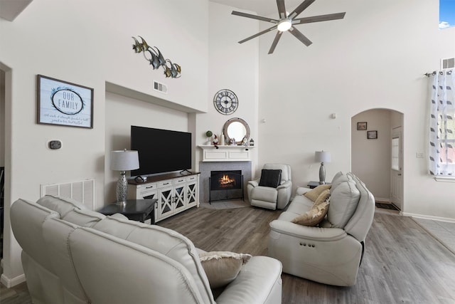 living room featuring wood-type flooring, ceiling fan, and a high ceiling