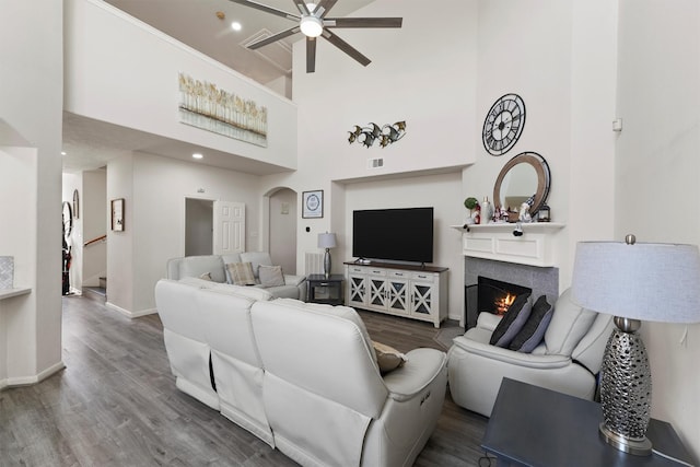 living room featuring hardwood / wood-style floors, ceiling fan, and a high ceiling