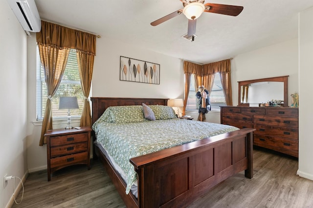 bedroom with dark hardwood / wood-style floors, ceiling fan, a wall unit AC, and multiple windows