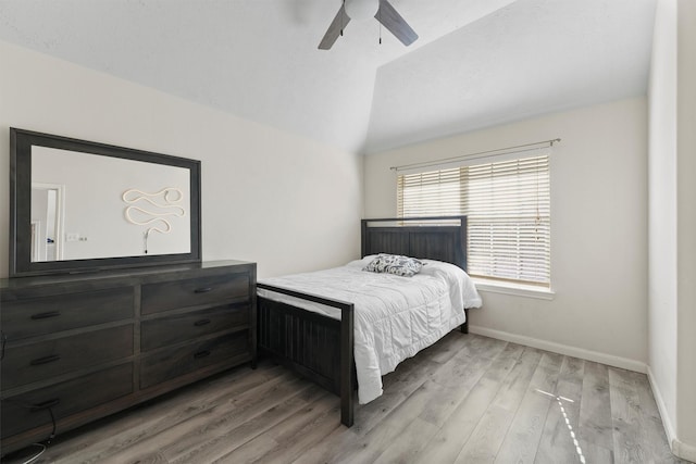 bedroom featuring ceiling fan, light hardwood / wood-style floors, and lofted ceiling