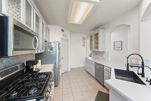 kitchen with decorative backsplash, appliances with stainless steel finishes, sink, light tile patterned floors, and white cabinetry