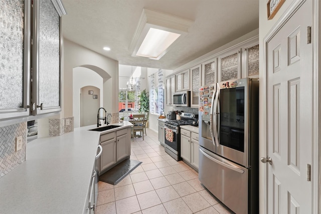 kitchen featuring sink, decorative light fixtures, decorative backsplash, light tile patterned floors, and appliances with stainless steel finishes