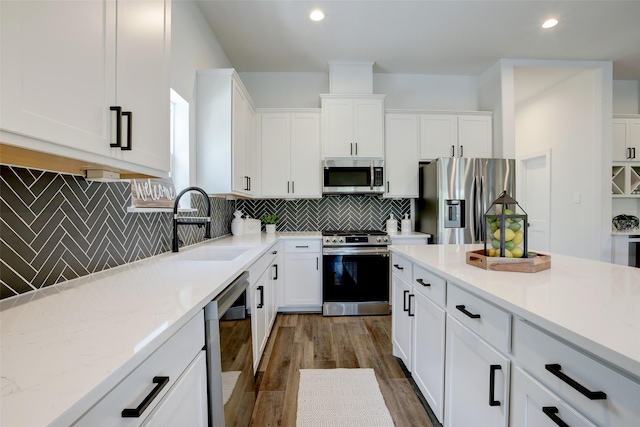 kitchen with tasteful backsplash, sink, white cabinets, and stainless steel appliances